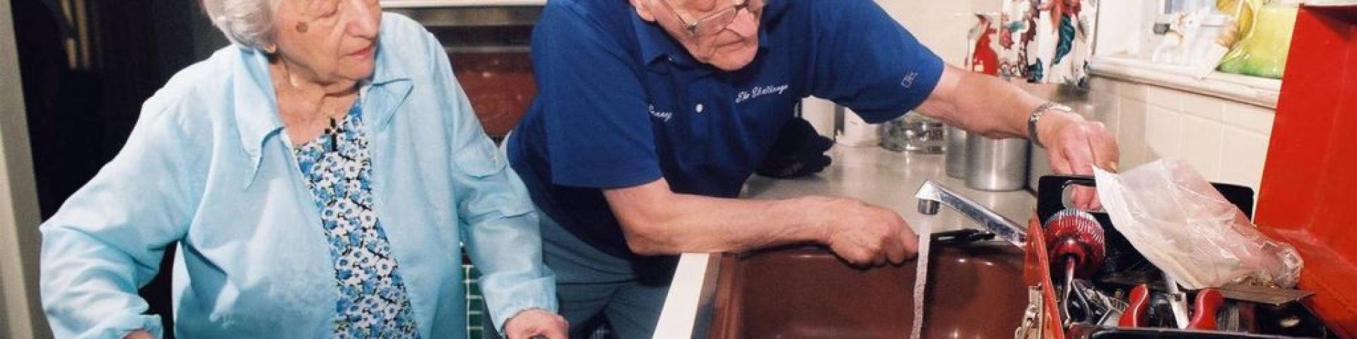 Picture of a husband helping his wife in the kitchen. Wife has a walker. 