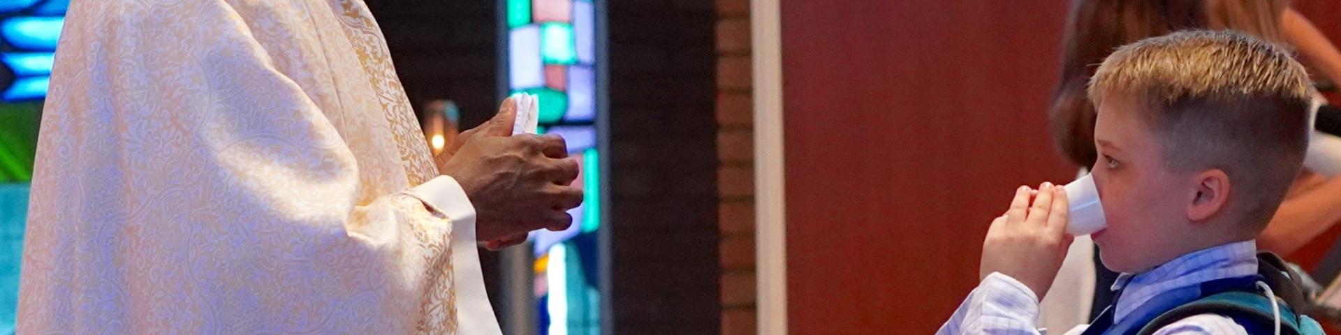 Carson receiving a piece of the Eucharist dissolved in a cup