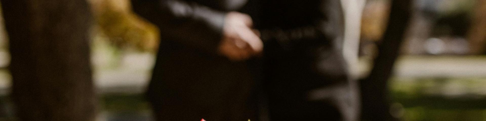 Flower on headstone with blurred image of couple in background.