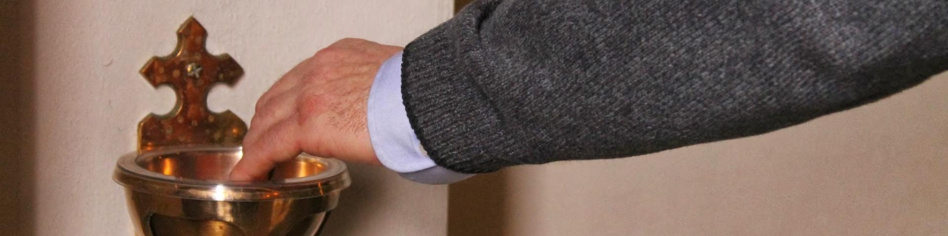 Man dipping hand into holy water font