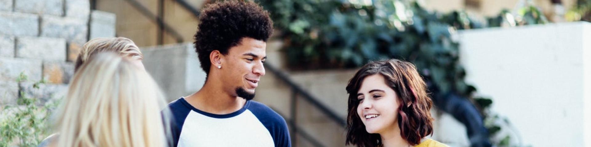 Three adolescents talking with one another on a city street 