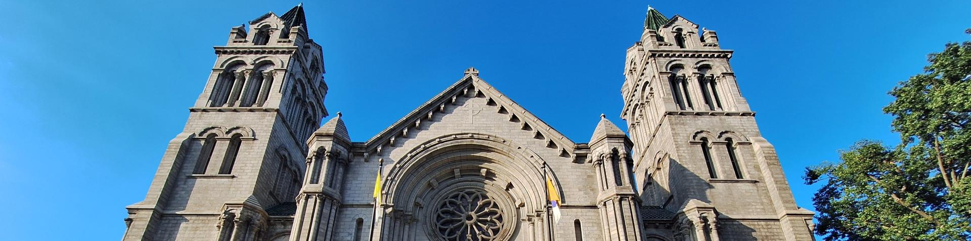 Outside, top of stone church with blue sky and a tree in the background.