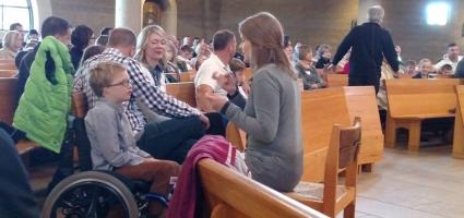 A sign language interpreter and a child in a wheel chair at Mass 
