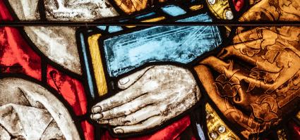 close-up of a stained glass window: a man holding a book