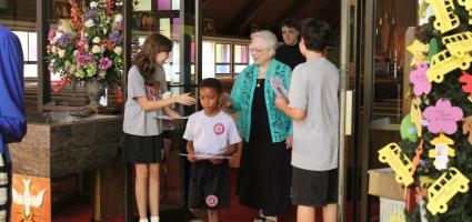 A person who is blind walking out of a Church with other parishioners