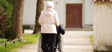 Woman pushes person in wheelchair toward church