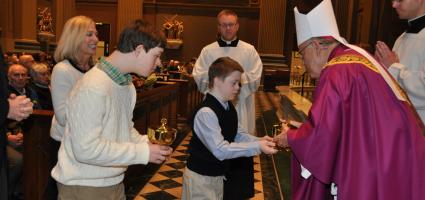 A person with down syndrome giving the gifts to a bishop