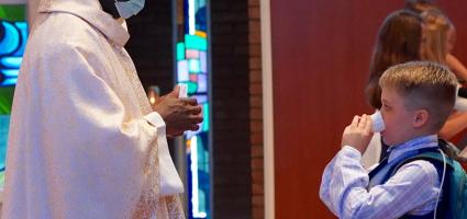Carson receiving a piece of the Eucharist dissolved in a cup