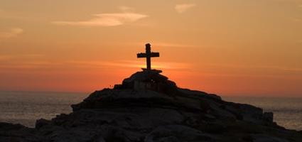 Cross on a hill with a sunset in the background