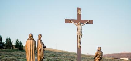 Crucifix in a field with  statue of Mary and Saint John 