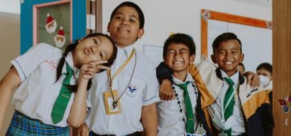Kids in school uniforms smiling and standing close together.