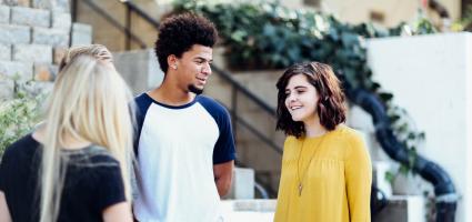 Three adolescents talking with one another on a city street 