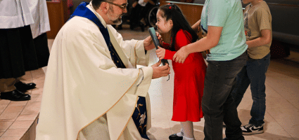 Priest kneeling to interact with children with disabilities