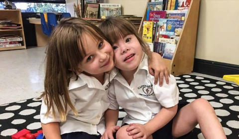 Two young girls in Catholic school, one with a disability