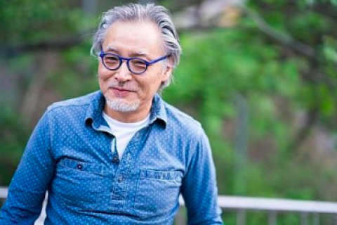 Man with glasses smiling with trees in the background