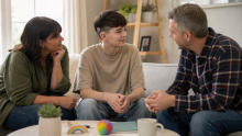 Boy, teen, with hearing aid talking to foster parents