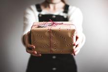 A teenage girl holding out a gift with candy cane wrapping paper