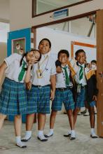 Kids in school uniforms smiling and standing close together.