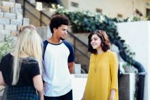 Three adolescents talking with one another on a city street 