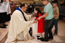 Priest kneeling to interact with children with disabilities