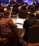 Two people sitting at a table in front of the CSMG stage