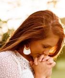 Young woman praying in field.